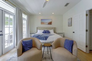 A bedroom with a bed, two armchairs, a small table, and a painting on the wall. - 5 Mi to UF! Luxury 2-unit Combo w/ Hot Tub (Gainesville)