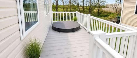 Una terrazza coperta con un'area salotto circolare, ringhiere bianche e un vaso con una pianta.
