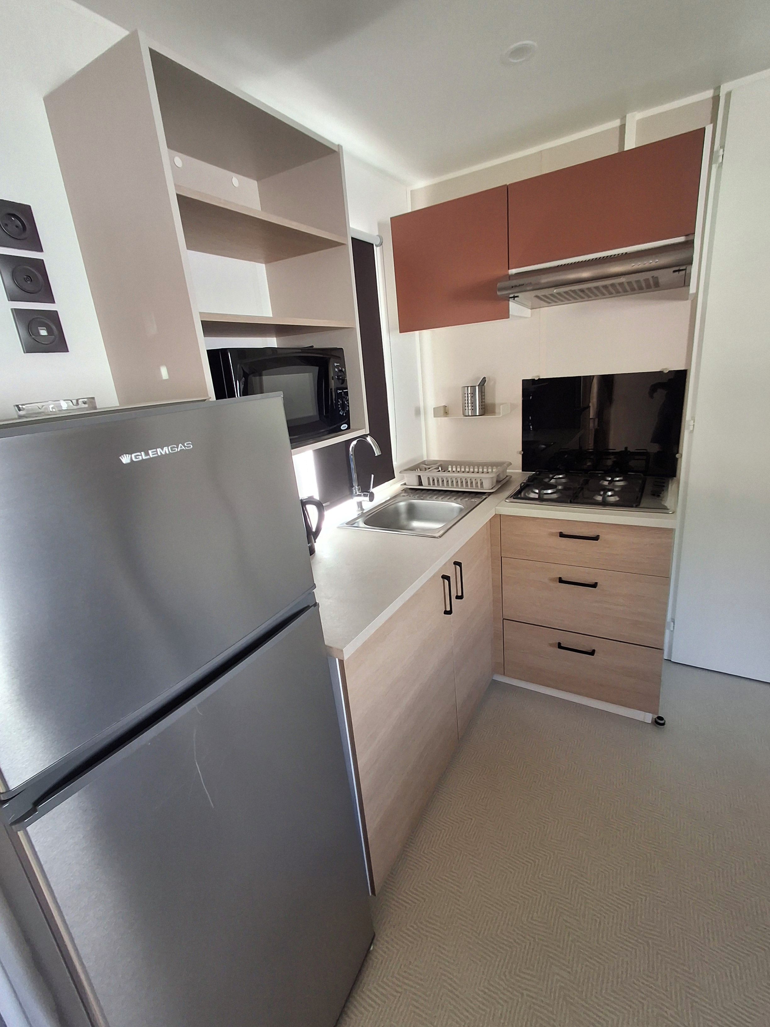 Cocina compacta con refrigerador, microondas, estufa y lavaplatos.