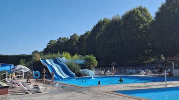 Een zwembad met een waterglijbaan en ligbedden.
