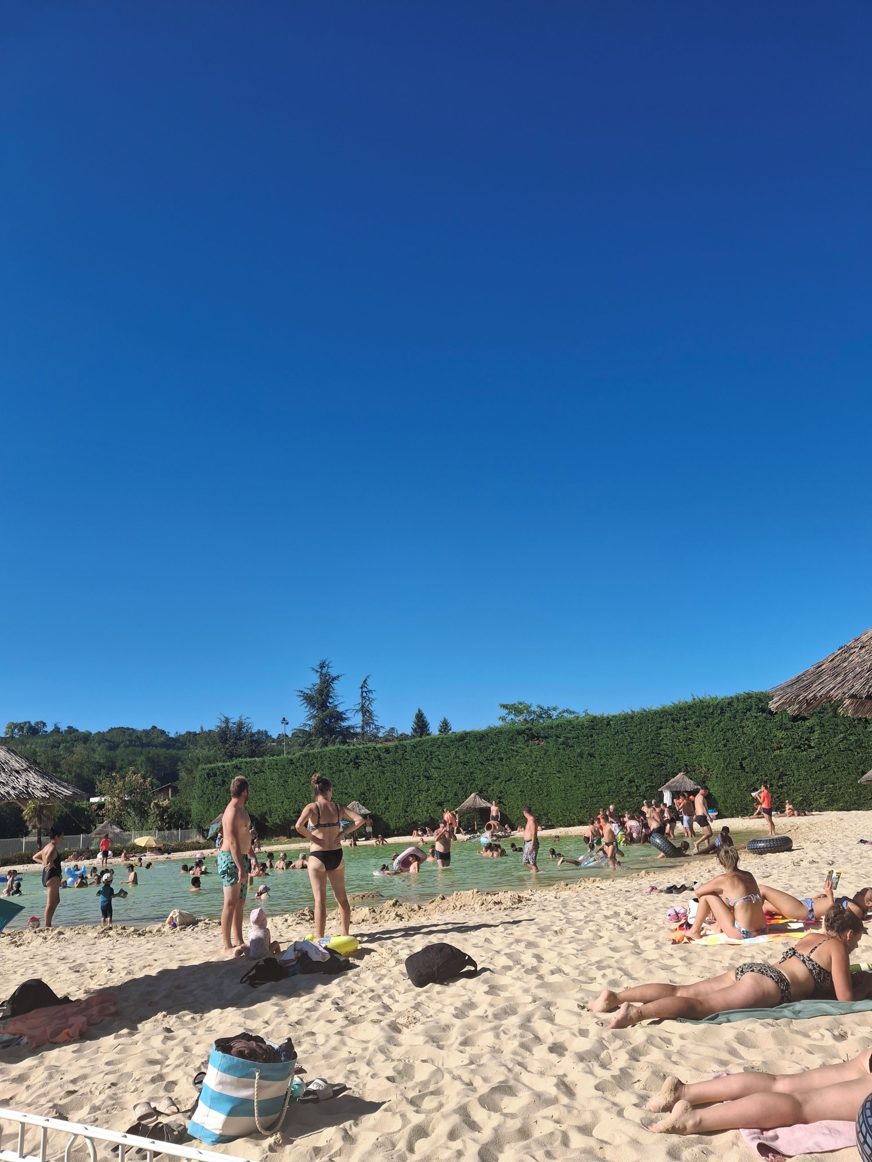 A beach with people sunbathing and swimming.