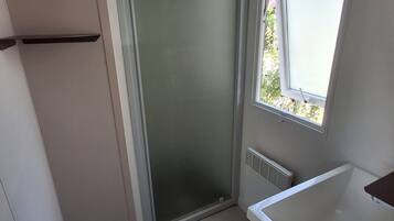A small bathroom with a shower, a window, and a white sink.