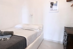 A single bed with a white mattress and pillows, a gray blanket, and a small bedside table with a lamp. - Ambrosia Cave Villa with Seaview & Private Pool (Exo Gonia)
