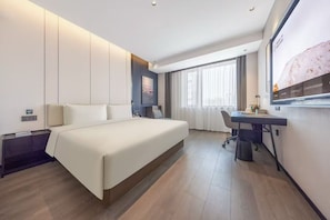 Quarto de hotel moderno com uma cama grande, uma escrivaninha e vista da cidade pela janela.