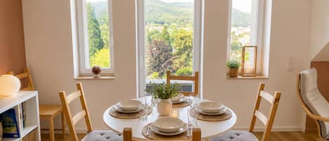 Comedor con una mesa redonda dispuesta para cuatro personas, rodeada de sillas de madera con asientos acolchados.