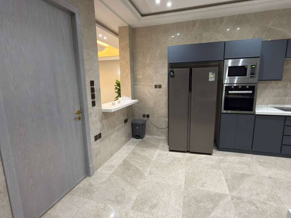 A modern kitchen with a stainless steel refrigerator, built-in oven, and microwave.