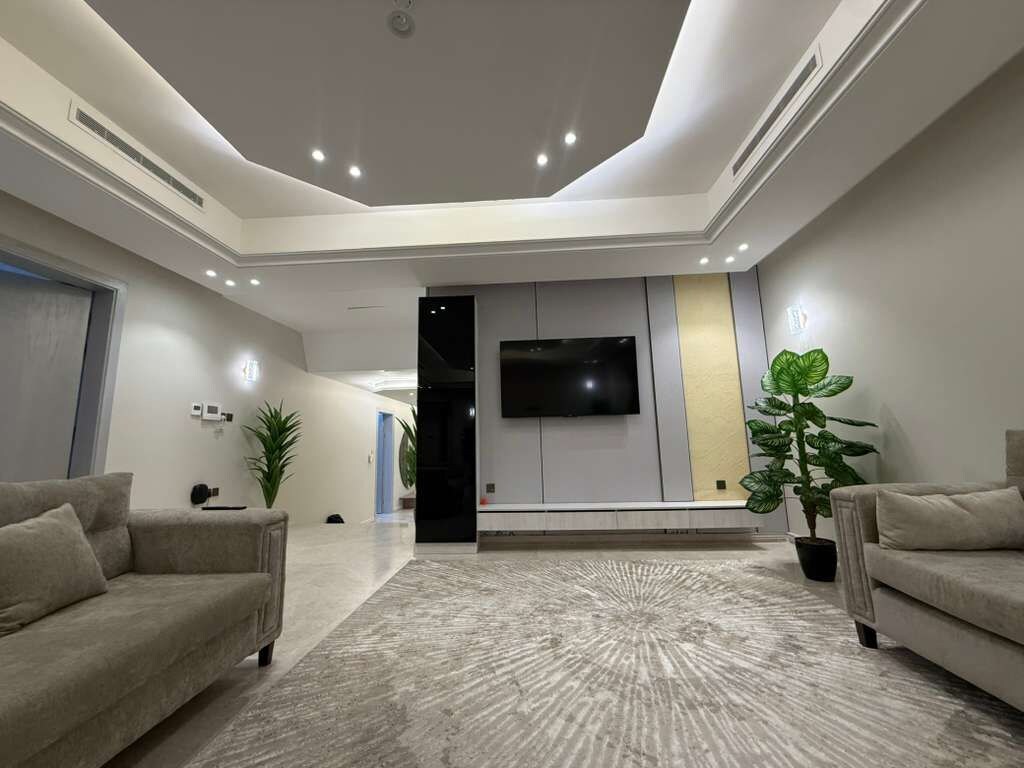 Una sala de estar moderna con un televisor de pantalla plana, dos sofás y un tapete estampado.