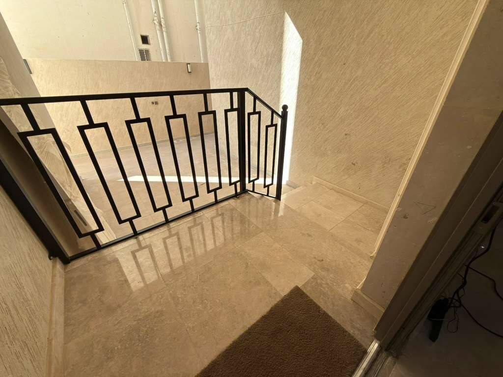 A staircase with a metal railing, beige walls, and a carpeted floor.