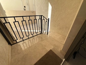 A staircase with a metal railing, beige walls, and a carpeted floor.