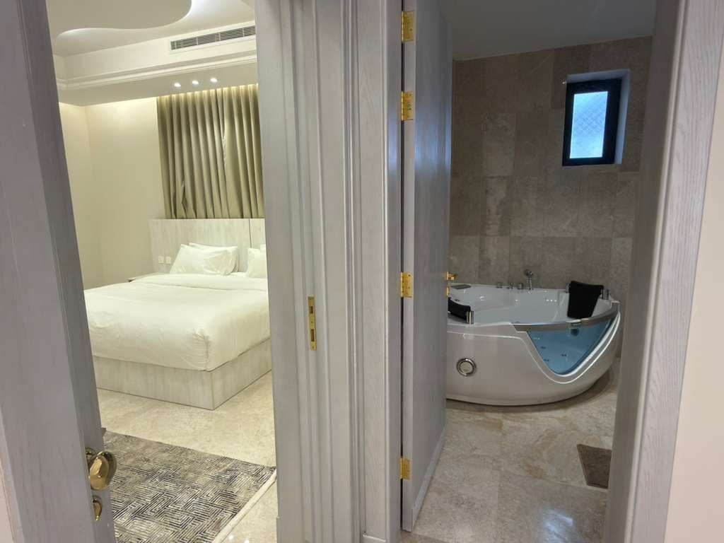 A modern bathroom with a bathtub, a small window, and a shower area.