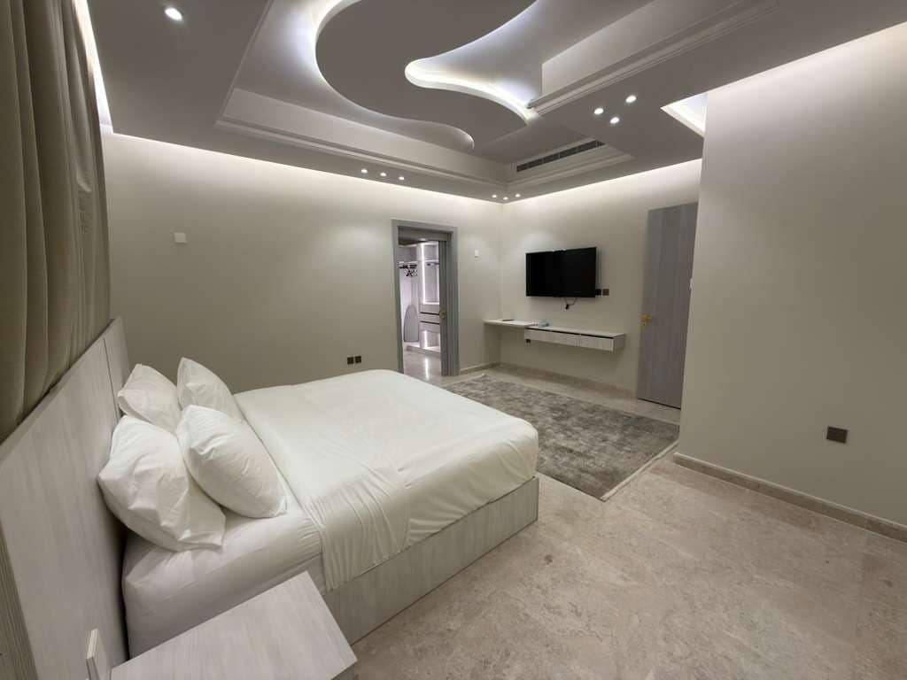 A modern bedroom with a bed, a flat-screen TV, and a walk-in closet.