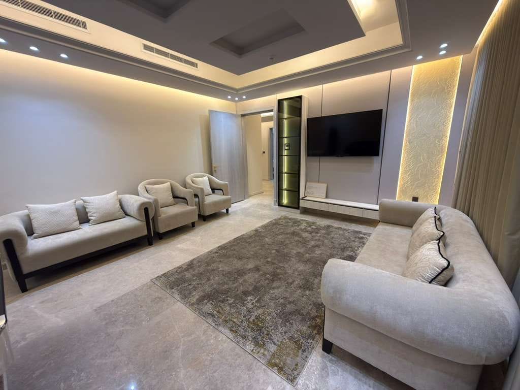 Una sala de estar moderna con un sofá seccional, un televisor de pantalla plana y un panel decorativo en la pared.