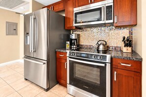 A kitchen with a stainless steel refrigerator, a Bosch oven, a microwave, and wooden cabinets. - Honua Kai | Mountain View 1 BR | Free Car w/ 6+ Nights | HKK-230 (Lahaina)
