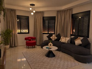 Ein modernes Wohnzimmer mit einem dunkelgrauen Sofa, einem roten Sessel und einem runden Couchtisch.