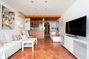 A modern living room with a sofa, coffee table, TV, and a kitchen area in the background. - Brand-new duplex with sea views. (CN)