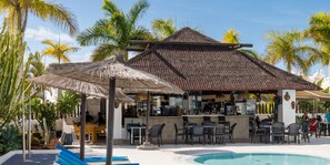 A poolside area with a bar, outdoor seating, and palm trees. - Brand-new duplex with sea views. (CN)