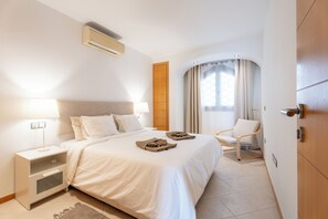 A hotel room with a bed, a nightstand, a chair, and a window with curtains. - Brand-new duplex with sea views. (CN)