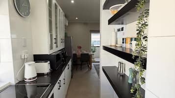 Una cocina moderna con armarios blancos, encimera negra y un reloj en la pared.