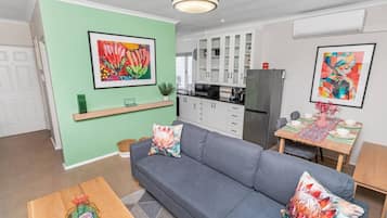 Una sala de estar moderna con un sofá gris, una mesa de centro de madera y un comedor con una mesa lista para dos.