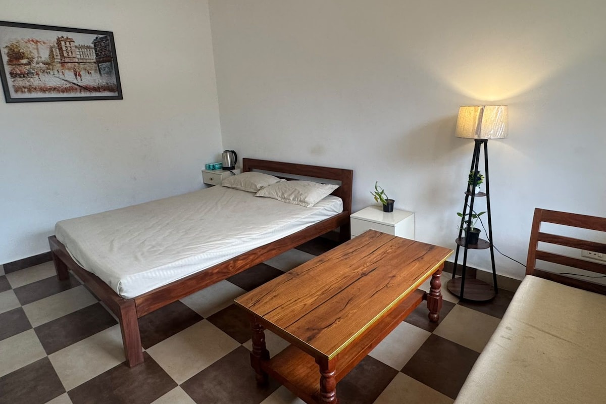 A single bed with a wooden frame, a bedside table with a lamp, and a checkered floor.