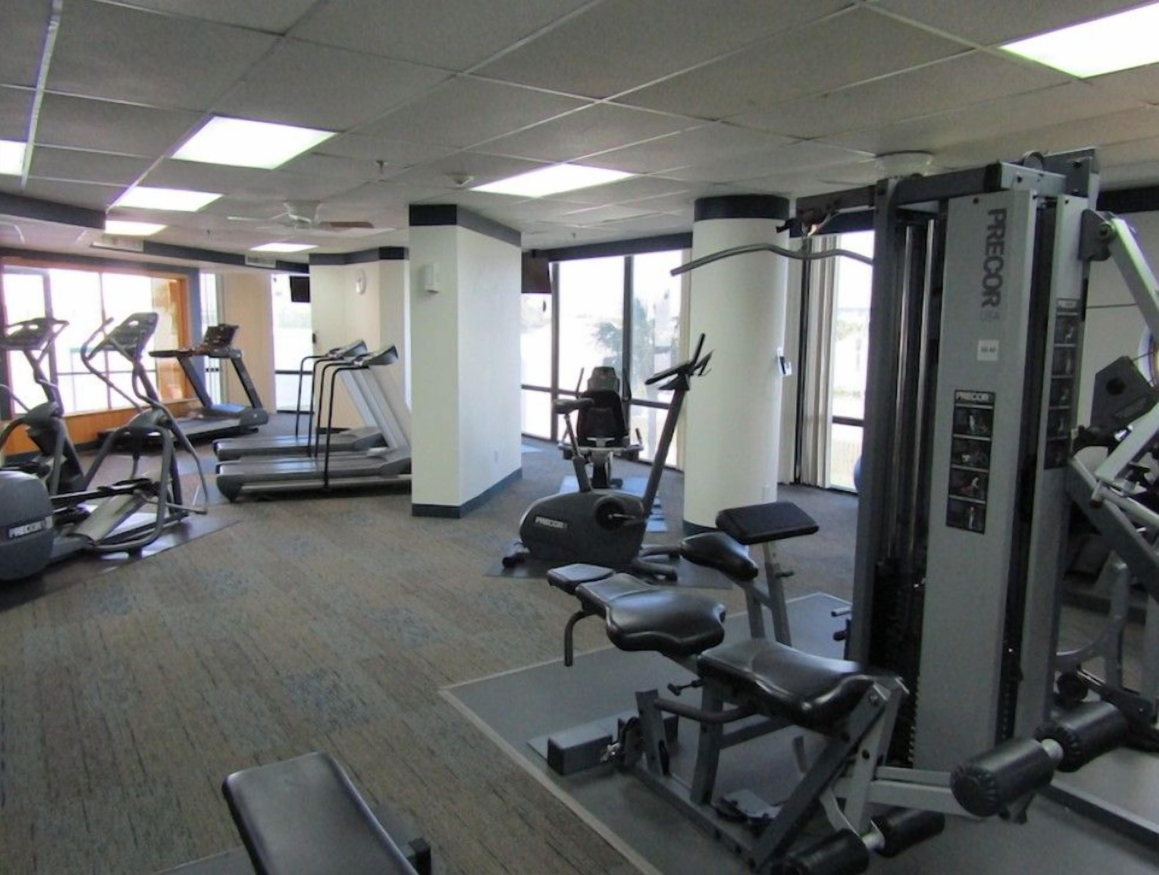 Une salle de sport équipée de tapis de course, de vélos elliptiques et de matériel de musculation.