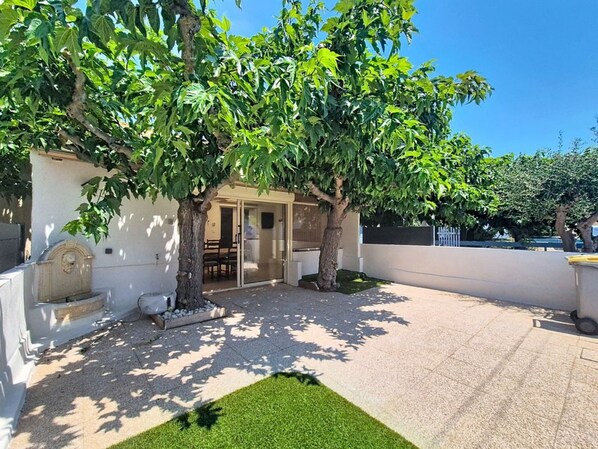 A courtyard with a building, two trees, and a small grassy area. - Fully renovated vacation home, an 8-minute walk from the ocean (Vendres)
