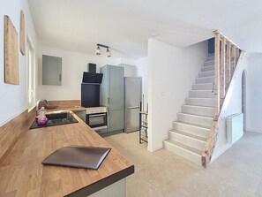 A modern kitchen with a wooden countertop, stainless steel appliances, and a staircase leading to an upper level. - Fully renovated vacation home, an 8-minute walk from the ocean (Vendres)