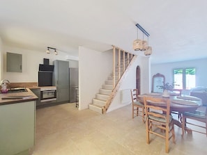 A spacious living area with a kitchen, a dining table, and a staircase leading to an upper floor. - Fully renovated vacation home, an 8-minute walk from the ocean (Vendres)