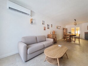 A modern living room with a sofa, a wooden coffee table, and a dining area with wooden furniture. - Fully renovated vacation home, an 8-minute walk from the ocean (Vendres)