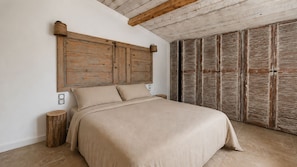 A bedroom with a bed, wooden headboard, and a wardrobe with shutters. - Fully renovated vacation home, an 8-minute walk from the ocean (Vendres)