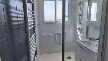 A modern bathroom with a shower, toilet, and sink.