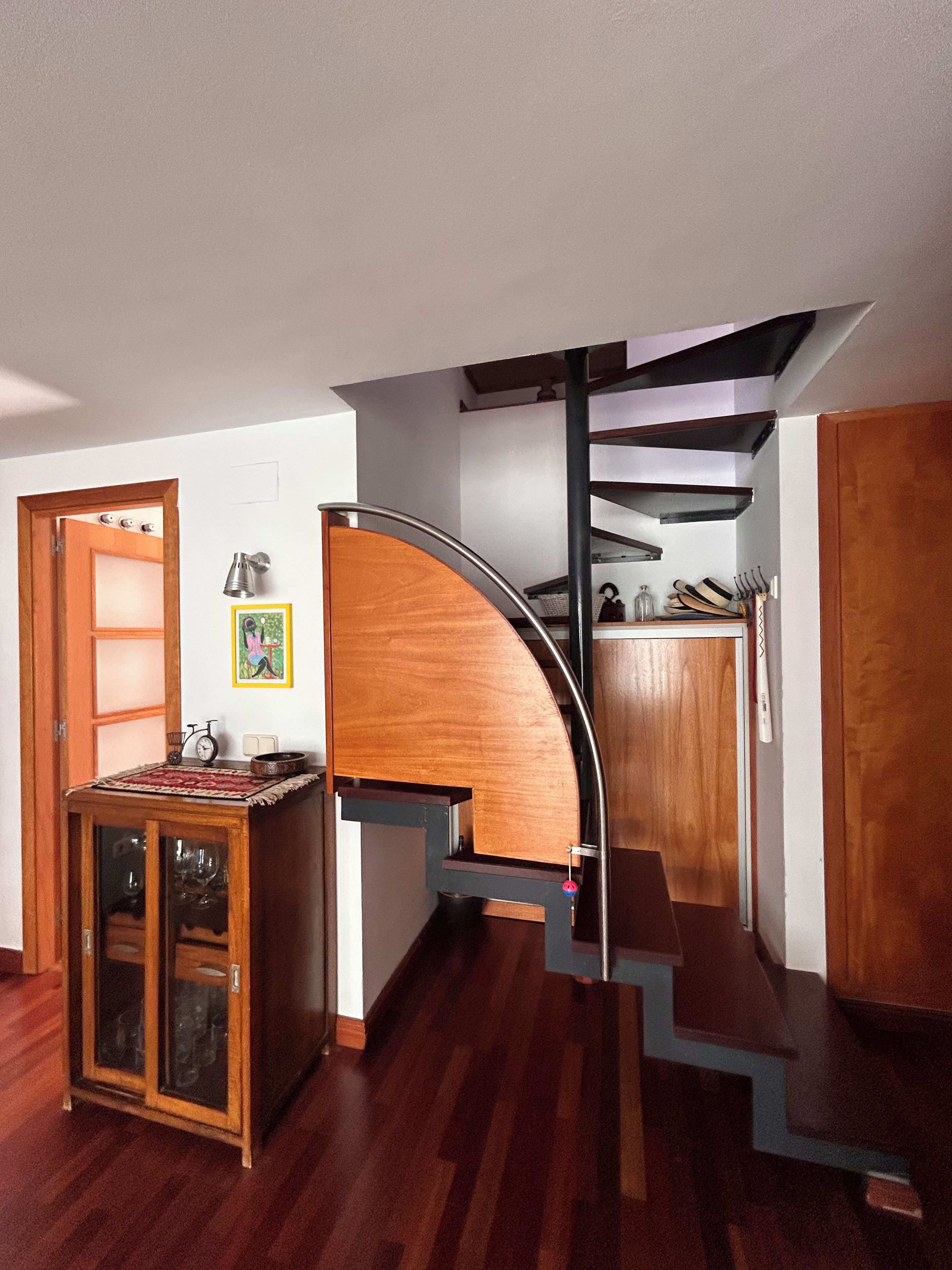 A staircase with a wooden finish and metal railings, leading to an upper floor.