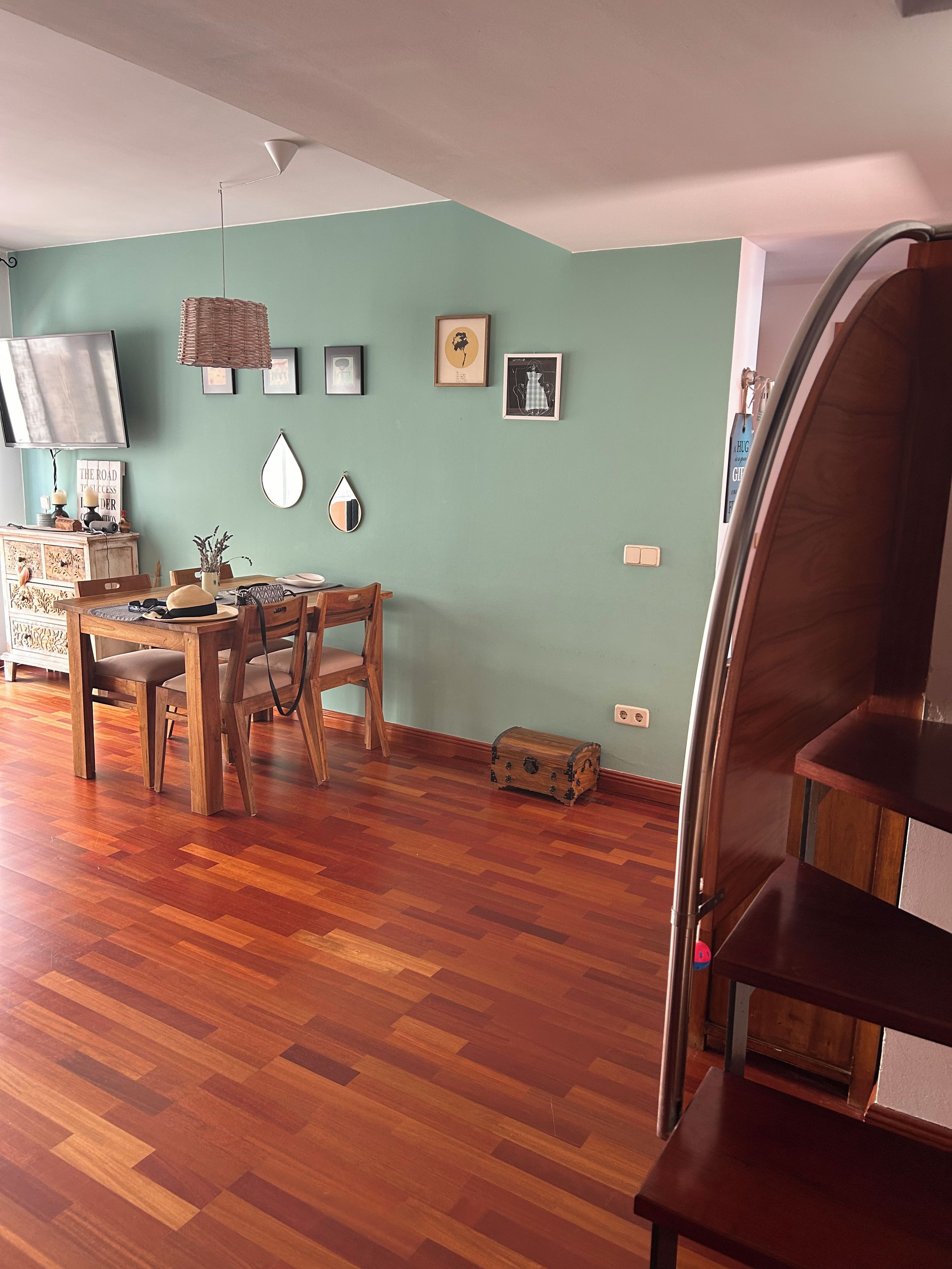 Un coin repas avec une table et des chaises en bois, un téléviseur et des décorations murales.