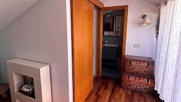 Una habitación con piso de madera, una chimenea blanca, una puerta de madera y un conjunto de cofres de madera con inscripciones.