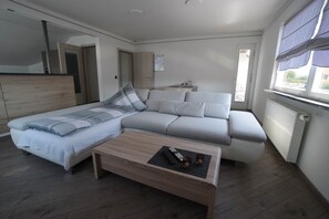 A modern bedroom with a bed, sofa, and a small table with remote controls and glasses. - David´s Apartment (Meckenbeuren)