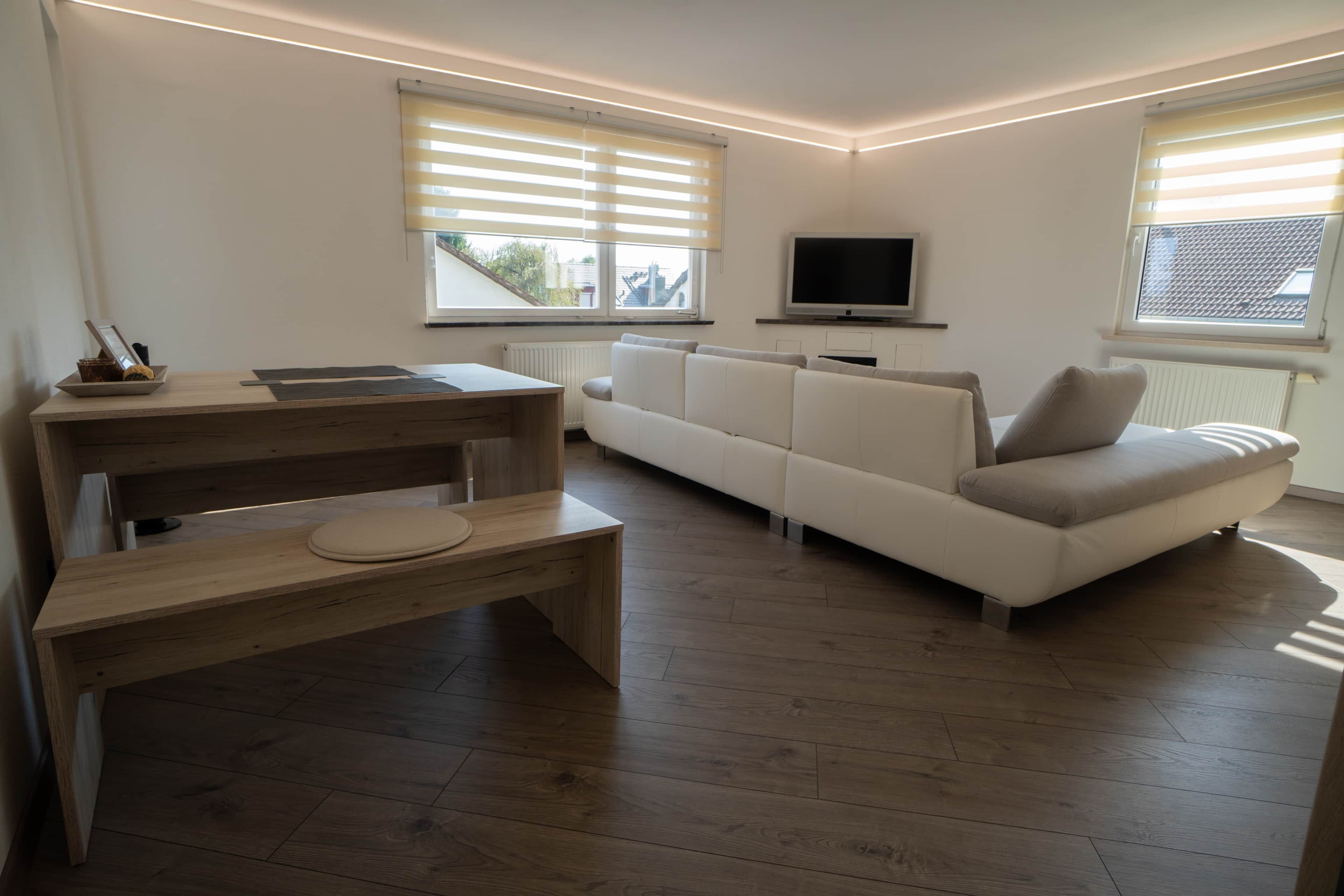 Un salon moderne avec un bureau en bois, un canapé et un téléviseur.