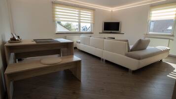 A modern living room with a wooden desk, a sofa, and a television.