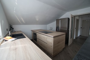 Une cuisine moderne dotée d’un plan de travail en bois, d’un four encastré et d’un réfrigérateur.