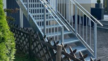 A building with a metal staircase leading to a door, a glass awning, and a wooden fence.
