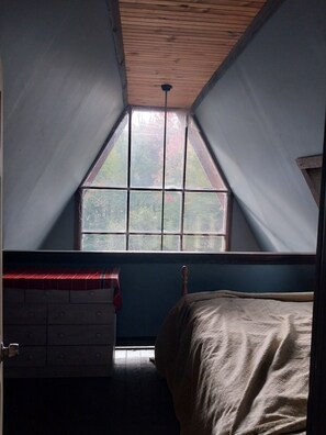 A room with a sloped ceiling, a window with a view of trees, a bed, and a dresser. - Beautiful 3-bedroom house in nice Dover perfect for your getaway (Dover)
