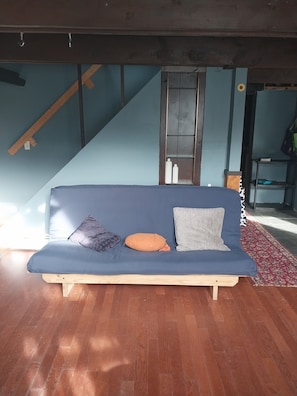 A room with a blue sofa, a wooden floor, and a staircase. - Beautiful 3-bedroom house in nice Dover perfect for your getaway (Dover)