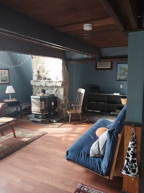 A cozy living room with a stone fireplace, wooden furniture, and a blue sofa. - Beautiful 3-bedroom house in nice Dover perfect for your getaway (Dover)