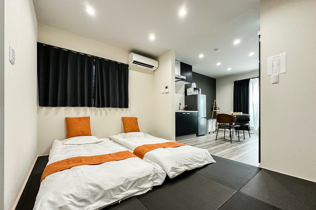 A hotel room with two beds, a kitchenette, and a dining area.