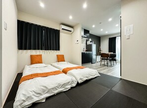 A hotel room with two beds, a kitchenette, and a dining area. - HANASTAY IWA (Osaka)