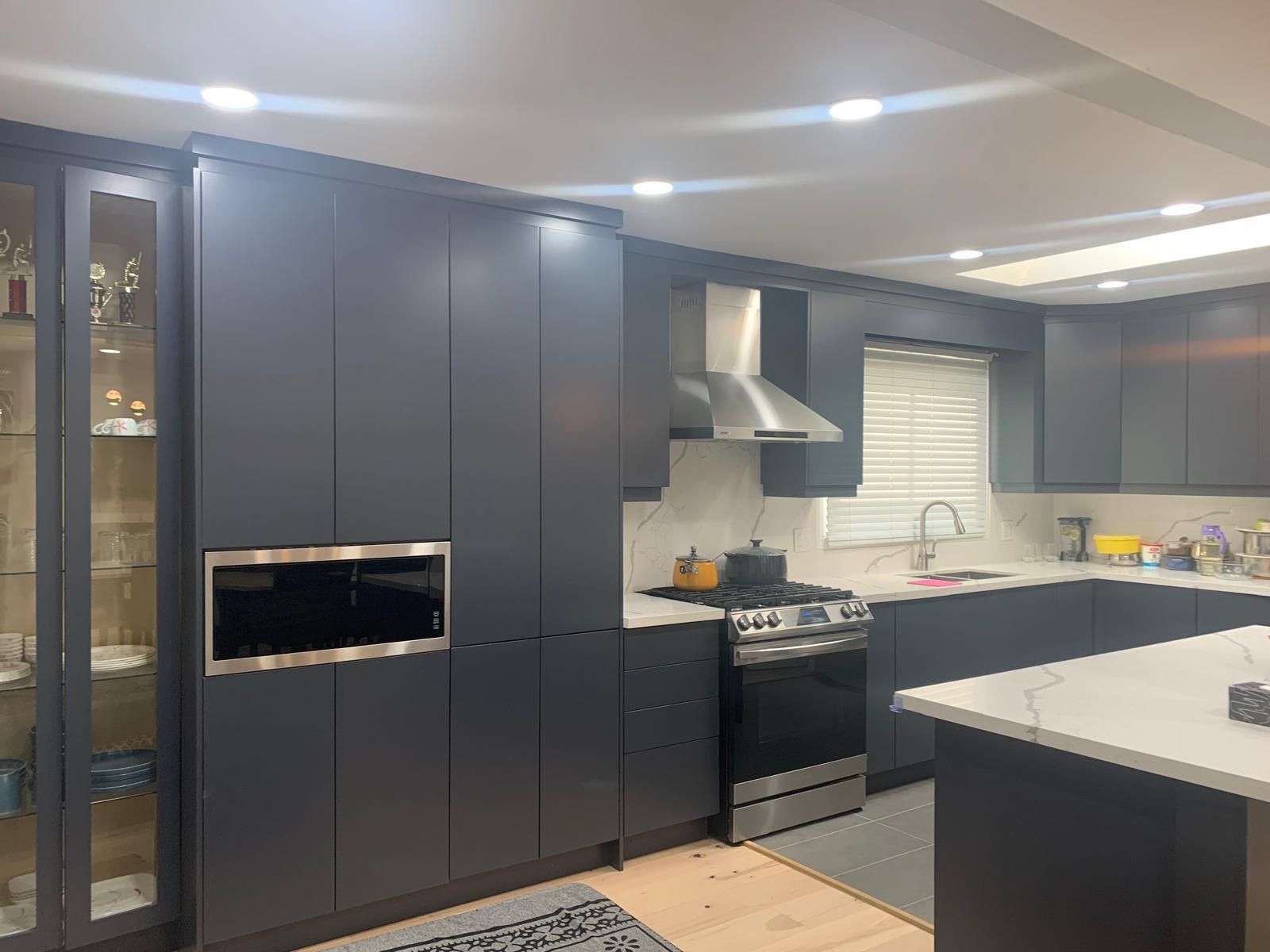 A modern kitchen with dark cabinetry, a built-in oven, and a microwave.