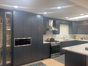 Una cocina moderna con armarios oscuros, horno empotrado y microondas.