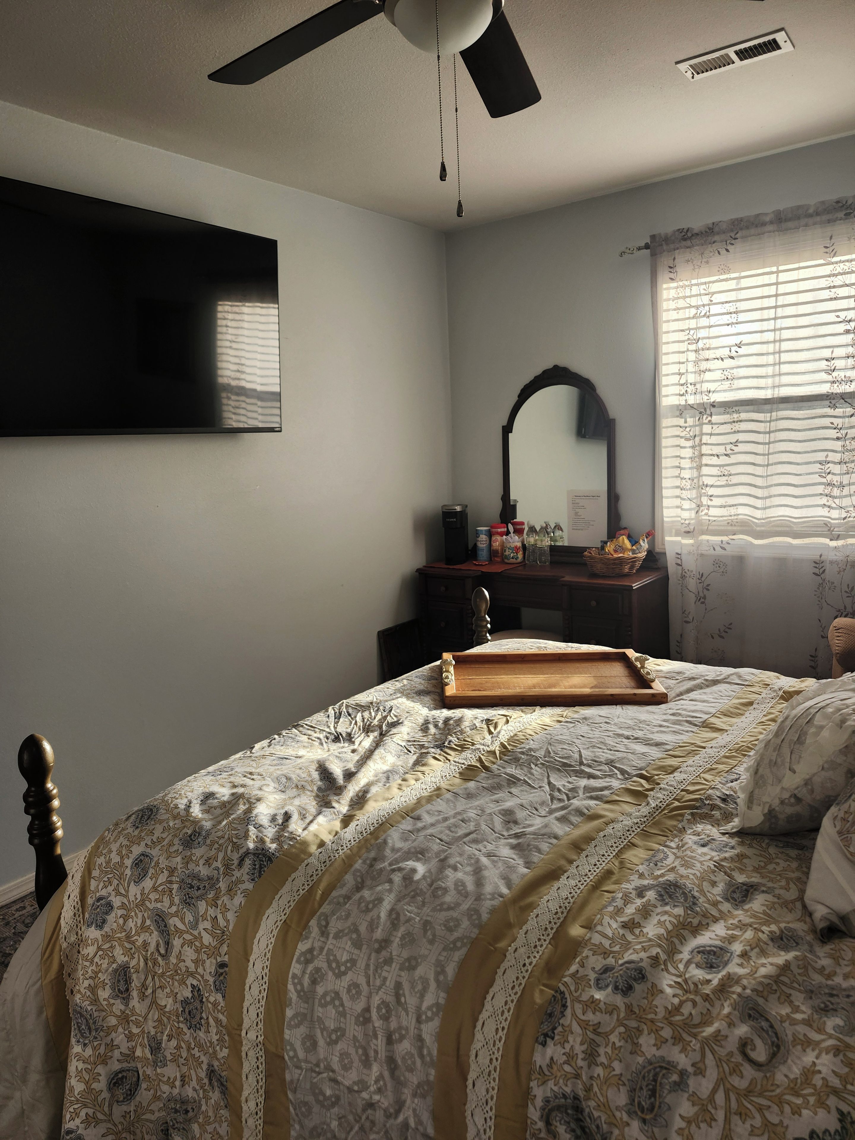 A bedroom with a bed, a dresser, a mirror, and a window with curtains.