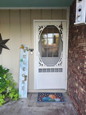 Una puerta blanca con paneles de vidrio decorativos, un cartel de bienvenida y una estrella decorativa.