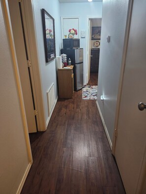 Un pasillo estrecho con piso de madera que conduce a una zona de cocina.
