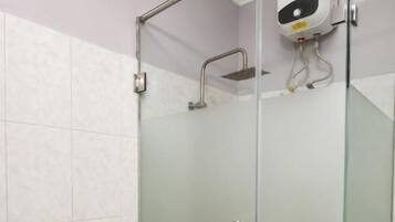 Cabina de ducha con paredes de vidrio, barra de apoyo y panel de control en la pared.